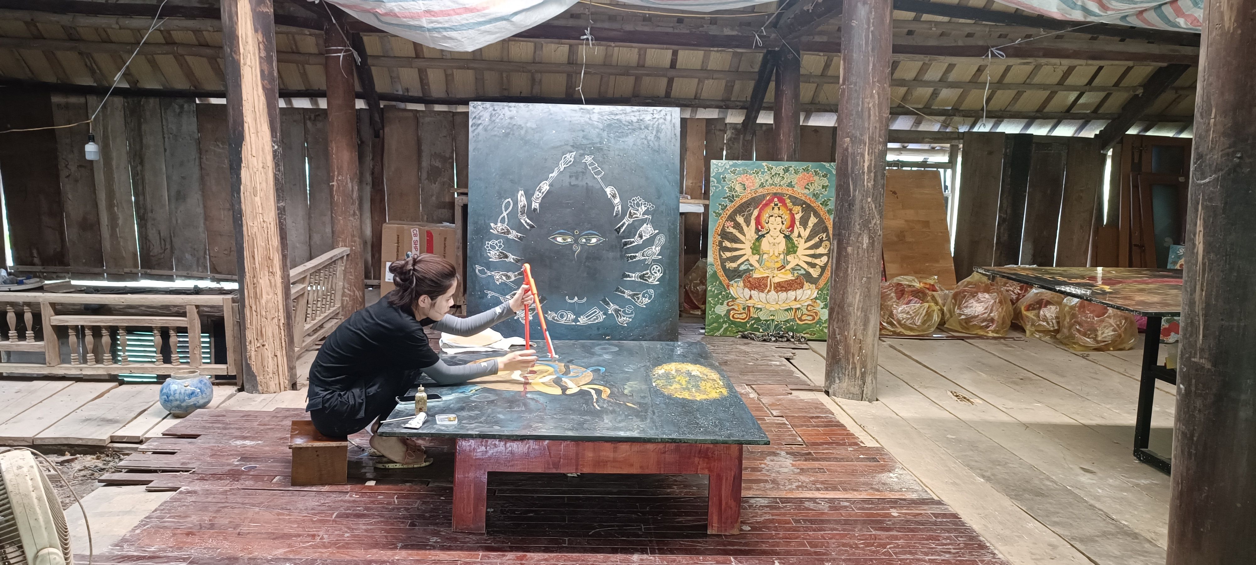 Học trò vẽ sơn mài, tranh Thangka phía sau